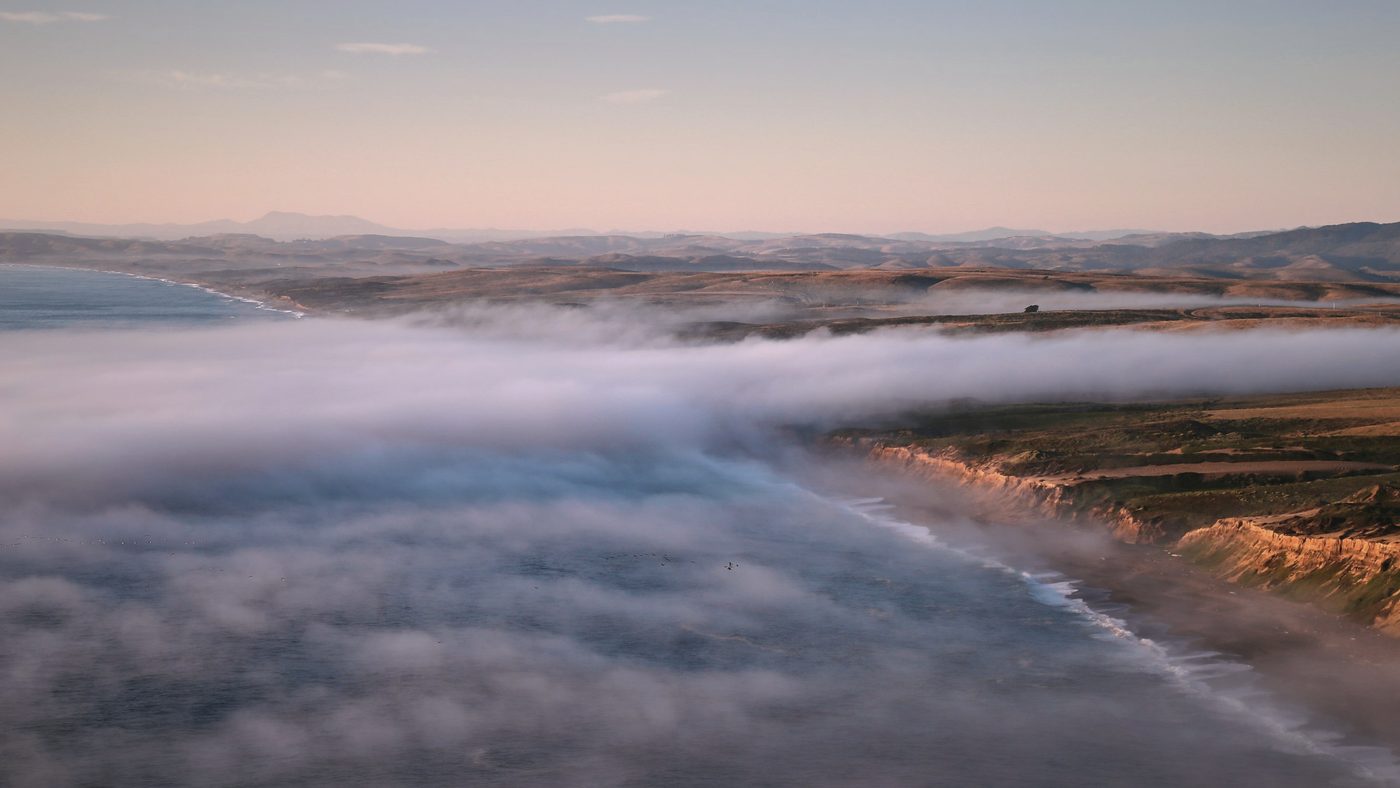 Low fog lying over the ocean along a line of coastal cliffs
